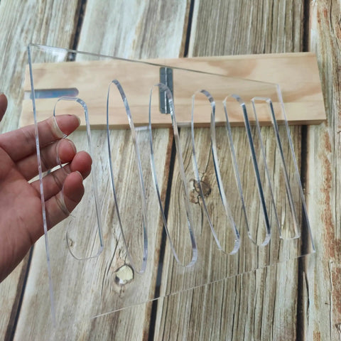 Top Shelf 6 In 1 Board Handle Router Template For Woodworking Pros Premium Clear Acrylic held in hand against wood background.