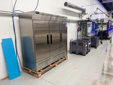 Rock Solid 82 Inch Wide Commercial Reach In Freezer With Three Doors And 72 Cubic Feet Capacity Stainless Steel in a kitchen setup.