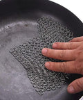 Hand using 8x6 Inch Cast Iron Chainmail Scrubber for Safe Scratch Free Cleaning of Pre Seasoned Pans Griddles Barbecue Grills and Pots