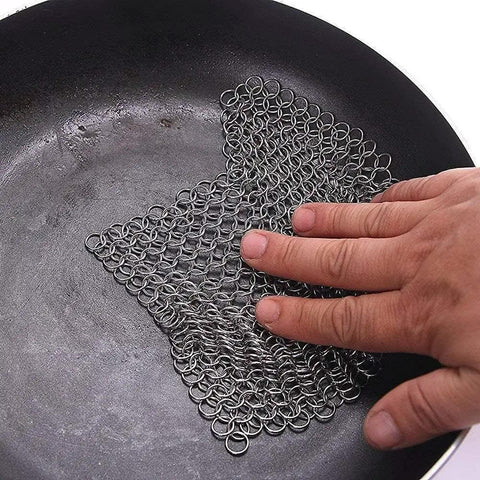 Hand using 8x6 Inch Cast Iron Chainmail Scrubber for Safe Scratch Free Cleaning of Pre Seasoned Pans Griddles Barbecue Grills and Pots