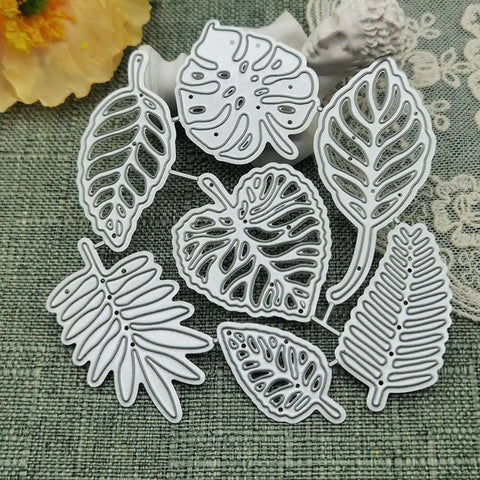 Totally Seven Piece Leaf Die Cut Set For Scrapbooking And Card Making; carbon steel dies in various plant leaf shapes on fabric background.