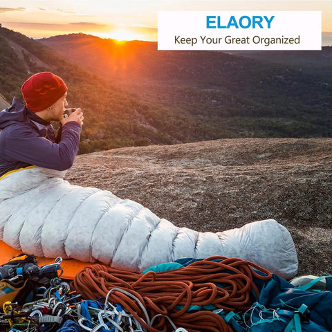 Person sitting on a mountain with a sleeping bag, sunrise view, climbing gear, ropes, outdoor adventure setup