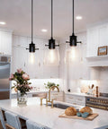 Black Pendant Lights For Kitchen Island, Modern Glass Hanging Fixture over a bright kitchen island with white cabinetry.