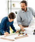 Father and son working on a craft project with a plan, using High Quality Game Changer Birch Dowel Rods For Craft Setup And Tiered Display 3/16 Inch X 15 Inch Pack Of Fifty Smooth Wood Sticks Perfect For Macrame Creations And Weekend Builds.