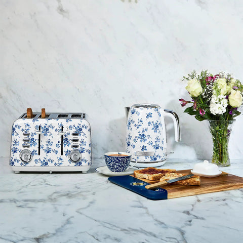 Floral electric kettle and toaster set with teacup, toast, and flowers on countertop.