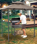 Man grilling under Outdoor Grill Gazebo 8 By 5 Foot Patio Canopy With Double Tier Roof And Air Vent And Eight Tool Hooks for backyard use.