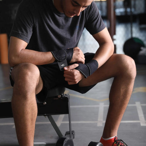 Man wearing two pack wrist compression straps and wrist braces for fitness and weightlifting, adjustable black neoprene support.
