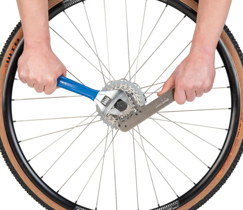 All In One Chain Whip And Pedal Wrench For Bike Maintenance, 10.75 Inch Steel Tool, being used on a bicycle wheel cassette
