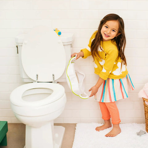 No Fuss Toddler Potty Training Seat With Rock Solid Non Slip Base Secure Handgrips And Quick Wipe Plastic Body For Smooth Potty Learning Journey In Bright Green held by girl near toilet.