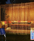 Solar Curtain Lights 300 LED Fairy String Lights With USB and Solar Dual Power lighting up a patio with cushions at night