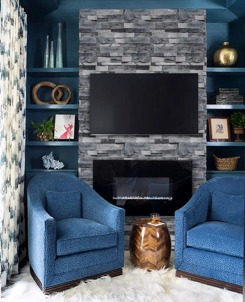 Living room with Grey Faux Brick Peel And Stick Wallpaper on fireplace wall, blue chairs, and modern decor.