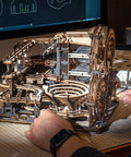 Person assembling 3D Wooden Marble Run Puzzle Kit For Adults with 294 Pieces, featuring mechanical gears in Night City theme.