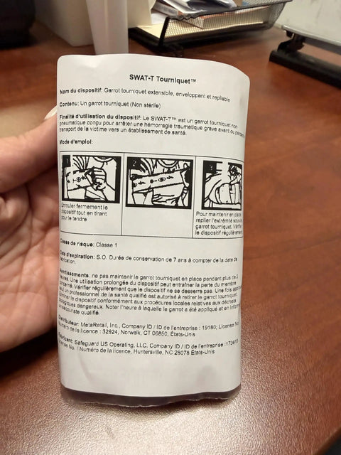Hand holding SWAT-T tourniquet instructions for Tourniquet Black For Quick Massive Hemorrhage Control With Stretch Wrap And Tuck System Ready For On Scene Emergency First Aid And Military Or Civilian Prehospital Care Made In USA.