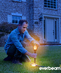 Man installing P2 Solar Flickering Flame Torch Light With Realistic Fire, IP65 Waterproof Outdoor Tiki Lamp in garden at dusk