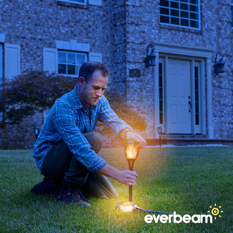 Man installing P2 Solar Flickering Flame Torch Light With Realistic Fire, IP65 Waterproof Outdoor Tiki Lamp in garden at dusk