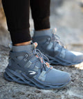 Man wearing Steel Toe Work Boots For Tough Jobs Lightweight Breathable Construction Boots High Cut Gray 45 on rocky ground