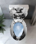 Elongated Resin Toilet Seat, Bathroom, featuring a humorous cow design on the lid with a blue toilet bowl visible, top view.