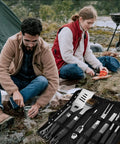 Camping scene with couple using 15 Piece Heavy Duty Stainless Steel Grill Tool Set With Long Sixteen And A Half Inch Spatula, Fork, Tongs.
