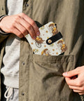 Person inserting Totally Clutch Vintage Rickshaw Bifold Wallet For Women Featuring Autumn Leaves Motif into jacket pocket.