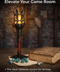 Medieval LED Torch Wall Sconce Flickering Flame Castle Light (Red) on a tabletop with gaming dice and a book.