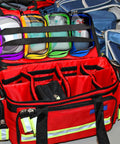 Front view of red first-aid bag opened to show eight color pouches with transparent windows and zipper compartments.