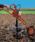 Kebayuneth 63CC gas-powered earth auger with orange frame, single wheel, drilling into soil.