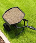 Top view of Broadcast Lawn Spreader With 9.8 Ft Coverage, filled hopper, on green grass, 10 in all terrain tires visible.