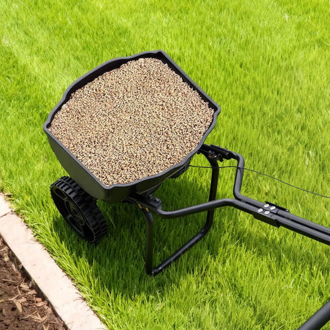 Top view of Broadcast Lawn Spreader With 9.8 Ft Coverage, filled hopper, on green grass, 10 in all terrain tires visible.