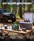 Camping setup with Portable On The Go Solar Generator Power Station with 288.6Wh capacity on a wooden table with cooler and camera.