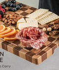 Real Deal Acacia Wood Checkered Cutting Board With Deep Juice Grooves And Solid Handles Large 17 Inch Butcher Block with snacks and fruit.