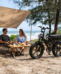 Adult Electric Bike, 750W Motor 1500W Peak Power beside a couple enjoying refreshments on the beach.