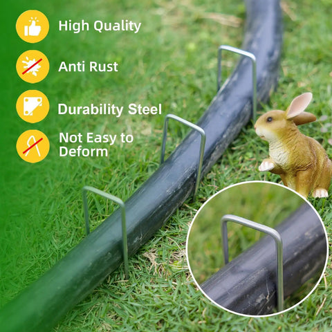 Tough As Nails Heavy Duty Galvanized 5 Inch Lawn Staples 11 Gauge U Shaped Ground Spikes securing a hose on grass.
