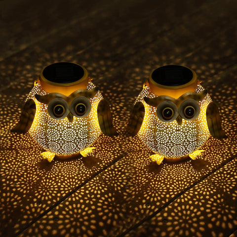 Two Pack Hanging Solar Lanterns With Owl Pattern Waterproof Metal Outdoor Garden Lights glowing on wooden surface at night