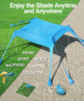 Sky blue Beach Tent 10 By 10 Ft Portable Shade Shelter set up on grass and sand with 8 sandbags and windproof ropes for family fun.