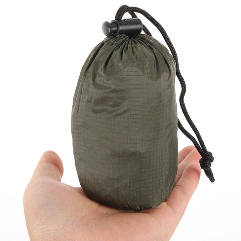 Hand holding green carry bag for Emergency Blanket Set With Green Aluminum Thermal Rescue Blanket And A Carry Bag For Camping And Hiking Survival Warmth In Outdoor Emergencies Lightweight And Compact With A Foldable Carry Bag For Hiking Camping Running And Disaster Prep.