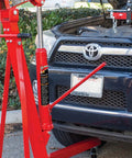 Image showing the Heavy Duty Hydraulic Long Ram Jack With Dual Piston Pump And Clevis Base For Garage And Shop Lifts 8 Ton Capacity 16000 Pounds being used with an engine hoist on a car.