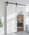 36 By 84 Inch White Sliding MDF Barn Door With Six Point Six Foot Black Sliding Door Hardware Kit And Handle Pre Drilled Ready To Assemble Waterproof PVC Coating shown installed in a living space.