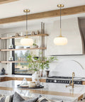 Single Opal Glass Pendant Light With Antique Brass Finish for a Cozy Modern Vibe, Warm Diffused Glow in a kitchen setting.