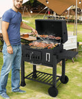 Man grilling on Barrel Charcoal Grill With Side Tables And Wheels, 544 Sq In Total Cooking Space, Portable Outdoor BBQ On Wheels