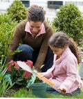 Child using Ergonomic Hand Shovel for Gardening, No-Fuss Grip, Dig Deep Spade for Planting in a garden with a parent watching.