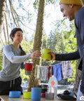 Campers using Two Person Camping Cook Set With Nesting Design Deep Dish Bowls And Double Wall Insulated Mugs in a forest setting