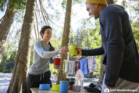 Campers using Two Person Camping Cook Set With Nesting Design Deep Dish Bowls And Double Wall Insulated Mugs in a forest setting
