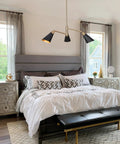 Three Light Modern Black And Gold Chandelier With Copper Brass Finish in a bedroom setting above a bed.