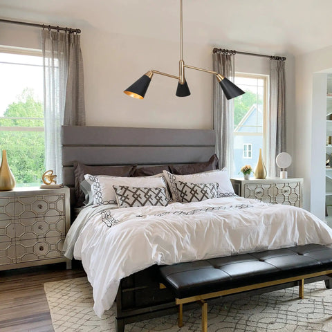 Three Light Modern Black And Gold Chandelier With Copper Brass Finish in a bedroom setting above a bed.