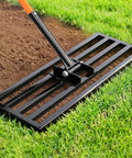Close-up of Heavy Duty Stainless Steel Lawn Leveling Rake with 78 Inch Adjustable Handle on grass and soil.