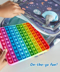Child placing a colorful Hundred Board Pop Fidget Toy For Kiddos, Sensory Bubble Popper into a space-themed backpack.