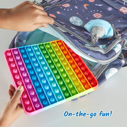 Child placing a colorful Hundred Board Pop Fidget Toy For Kiddos, Sensory Bubble Popper into a space-themed backpack.