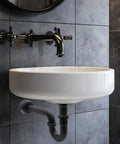 One And A Half Inch OD 17 Gauge Brass P-Trap With High Box Flange Matte Black Finish installed under a wall-mounted sink