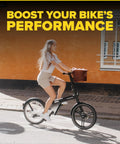 Woman riding a bicycle by a brick wall, basket in front
