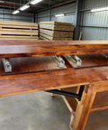 Solid 60 Inch Conveyor Roller Set, Galvanized Steel Rollers With Heavy Duty Brackets positioned on a woodworking table.